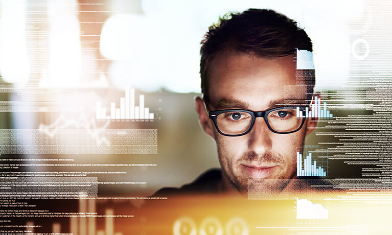man with glasses looking at data on screen