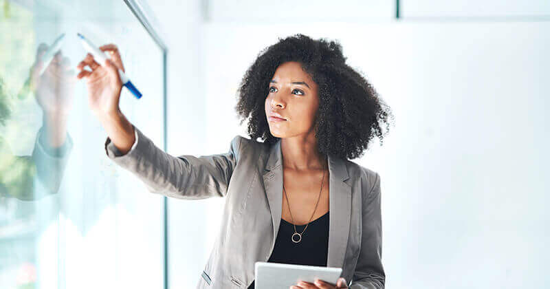 businesswoman in blazer writing on board