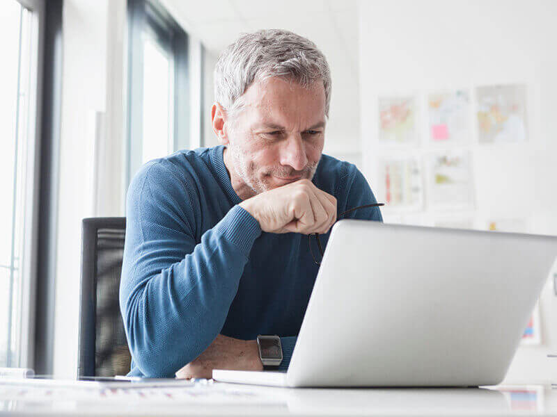 Mature man sitting using laptop