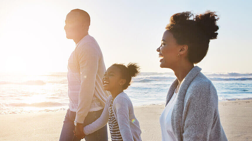 Family smiling and walking on beach