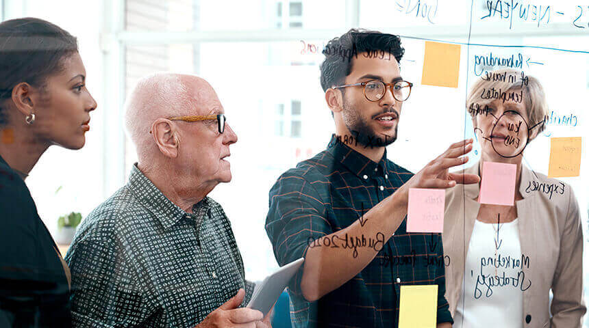 Team looking at glass board discussing ideas