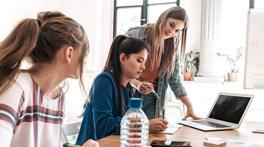 Three young women discussing at desk