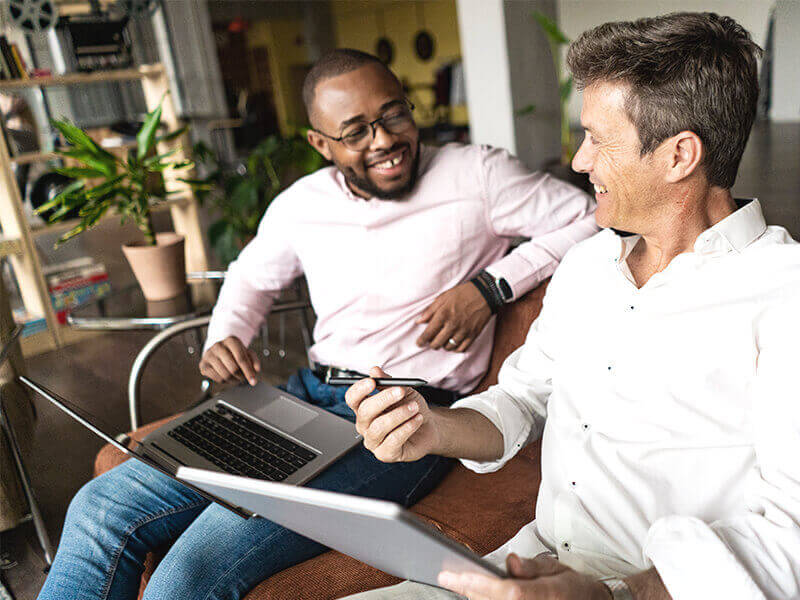 Two businessmen using laptop and tablet