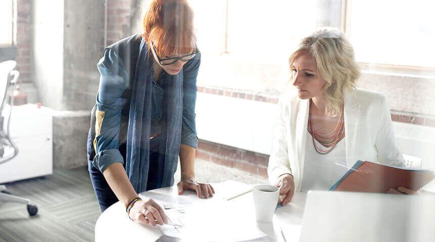 Two businesswomen look at work plan