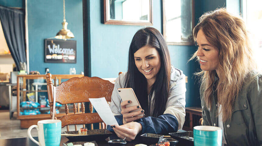 Two people looking at smart phone cafe