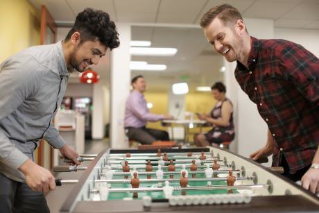 two employees playing air hockey together