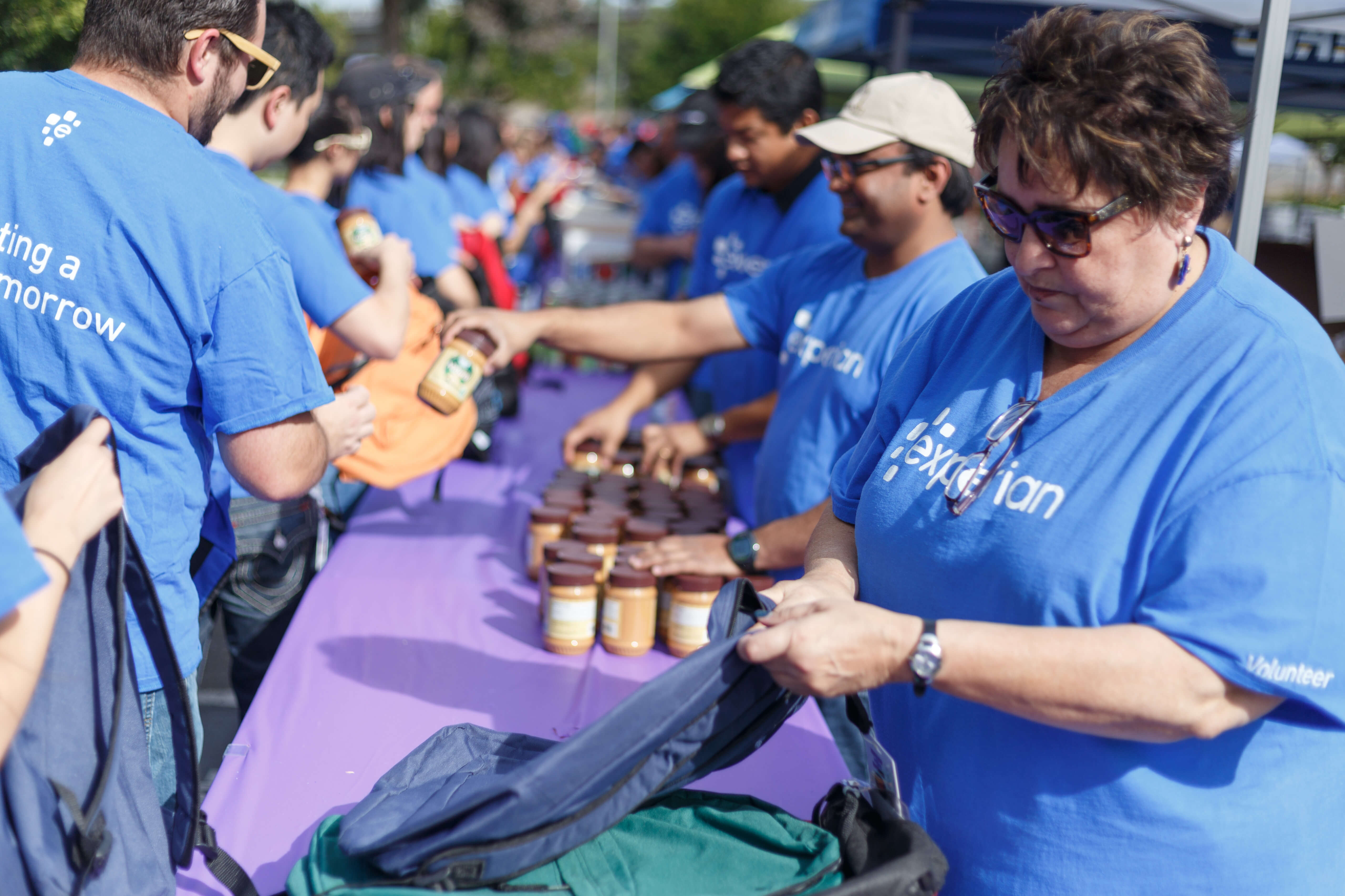 DEI Heart of Experian Volunteers packing backpacks of supplies