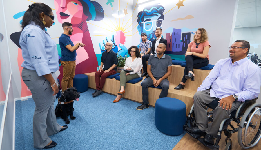 Black, blind woman with a guide dog speaking to a group of Experian employees
