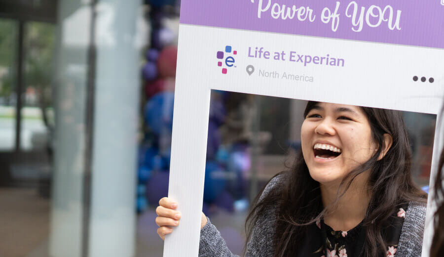 Laughing woman posing for a picture holding a Power of YOU cutout