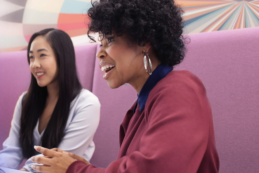 Two Experian employees sitting on a bench having a conversation with someone