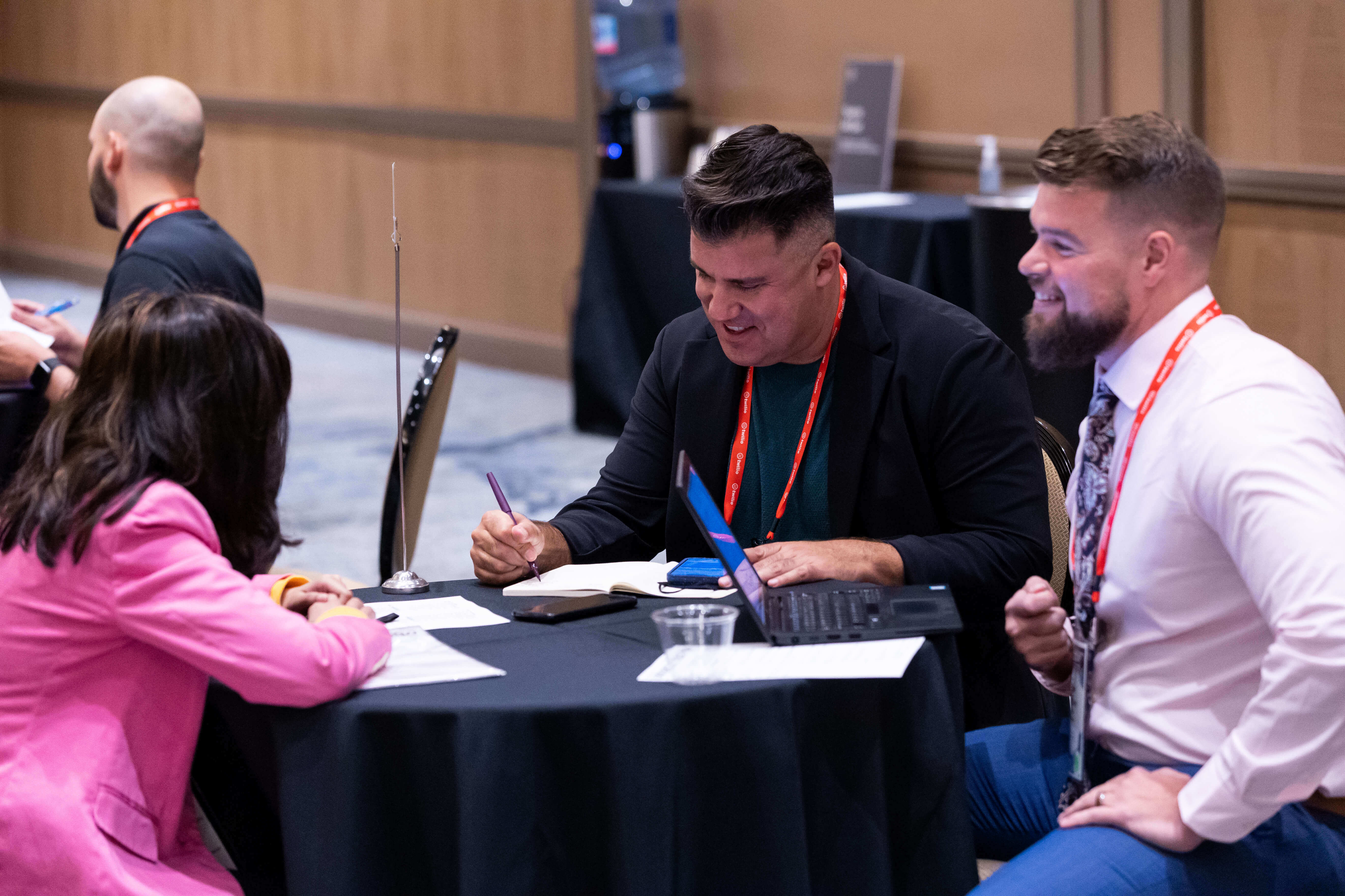 Two recruiters happily talking to a candidate at a conference