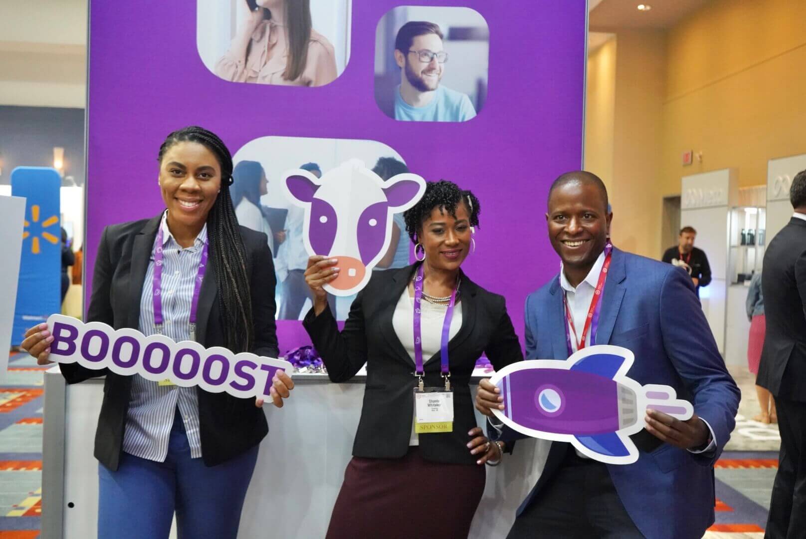 Three people holding up Experian Boost cutouts at a conference booth