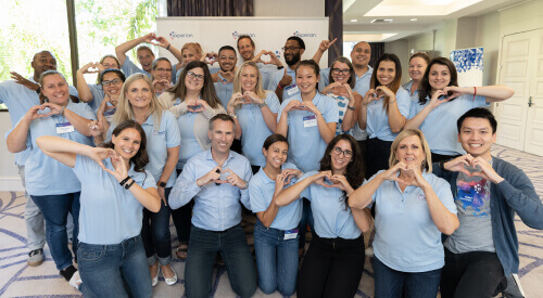 Large group of Experian volunteers posing for the camera by making a heart shape with their hands