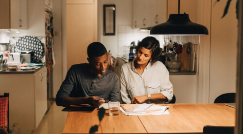 A man and a woman sitting at the kitchen table going over their finances