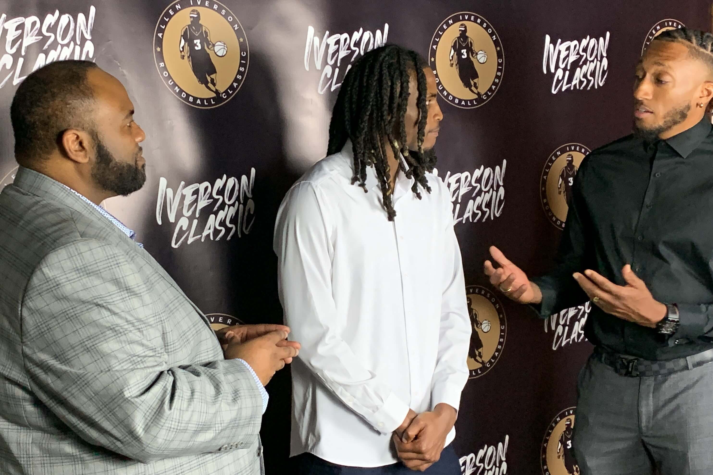 Two black men, including Lecrae, talking to a high school basketball athlete