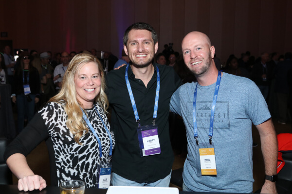 Harry stands between his coworkers at an Experian event.