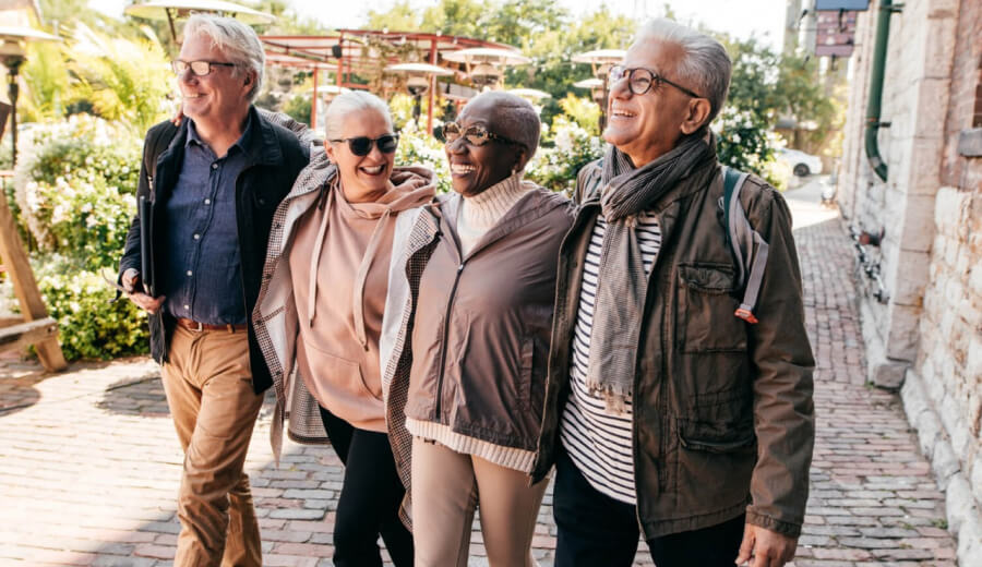 Four elderly people walking outside together