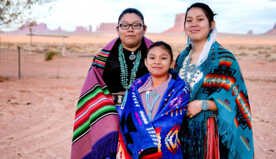 An indigenous family posing in the desert wearing cultural clothes
