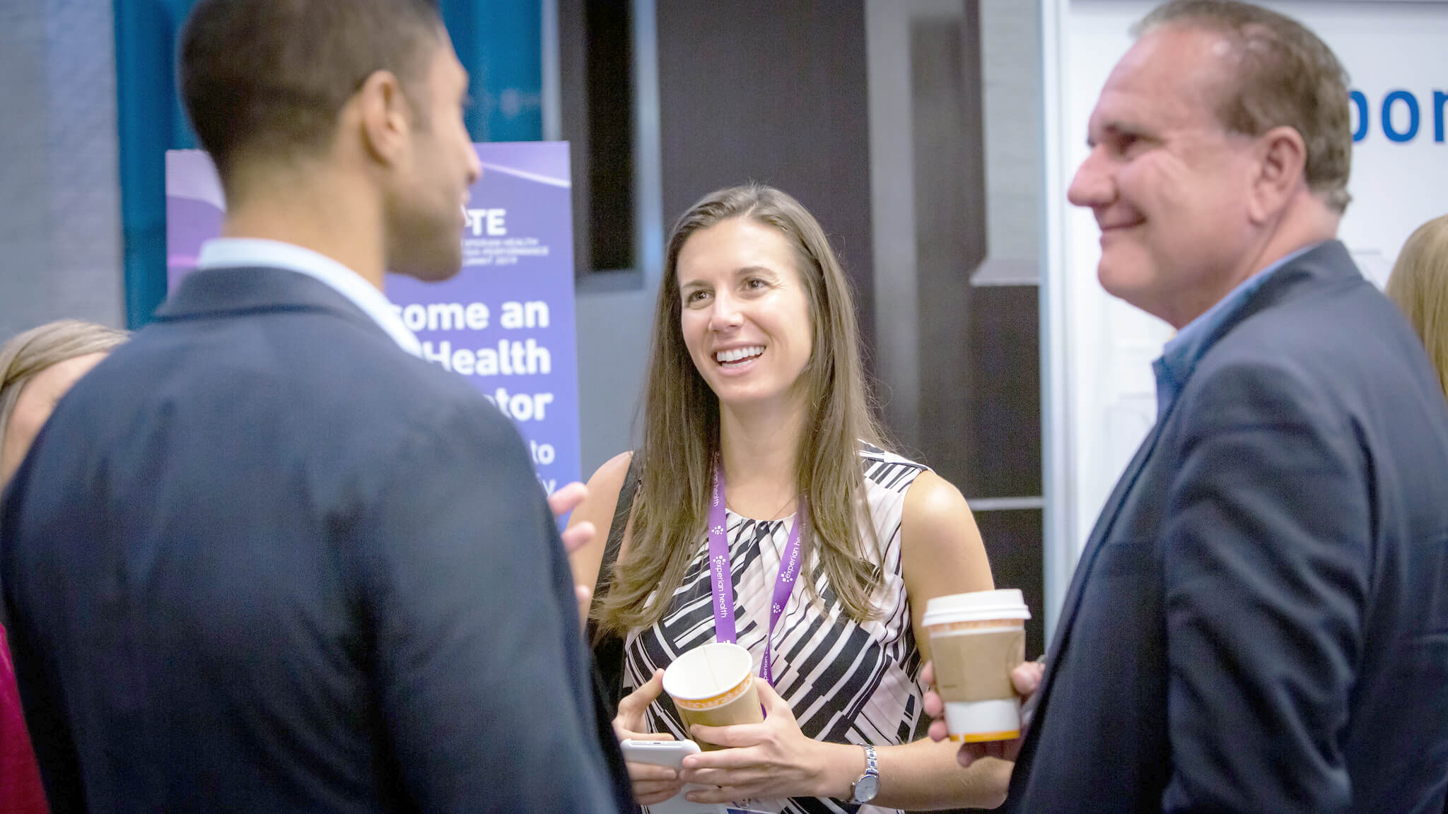 3 business people, cheerfuly talking at a networking event.