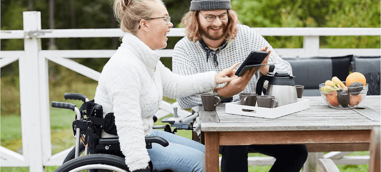 man and woman laughing and looking at tablet