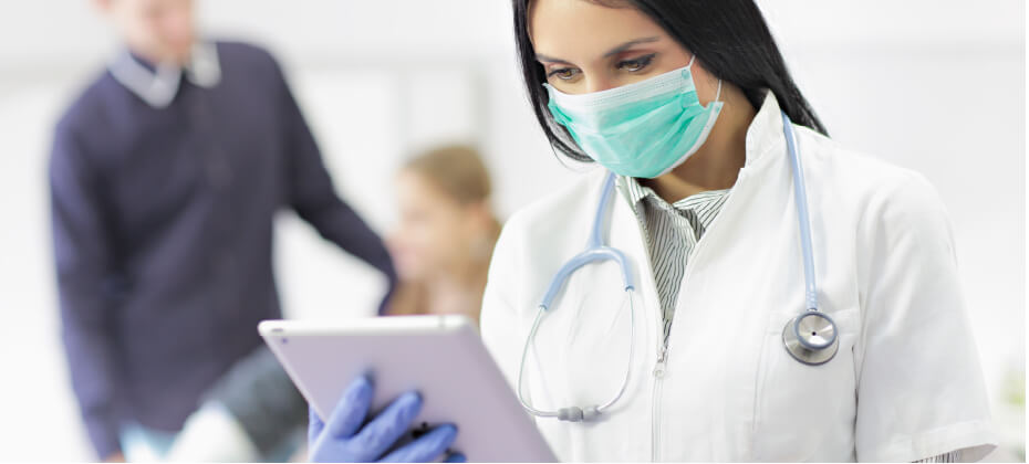 doctor wearing mask looking at tablet