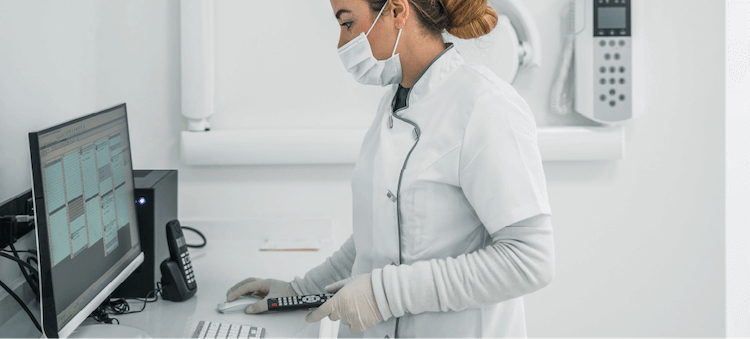 nurse looking at computer wearing mask