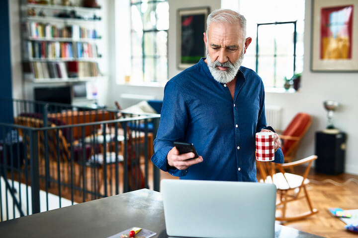 man at home holding phone to register online