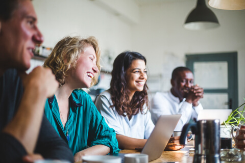 a diverse group of people in an office meeting, smiling and laughing